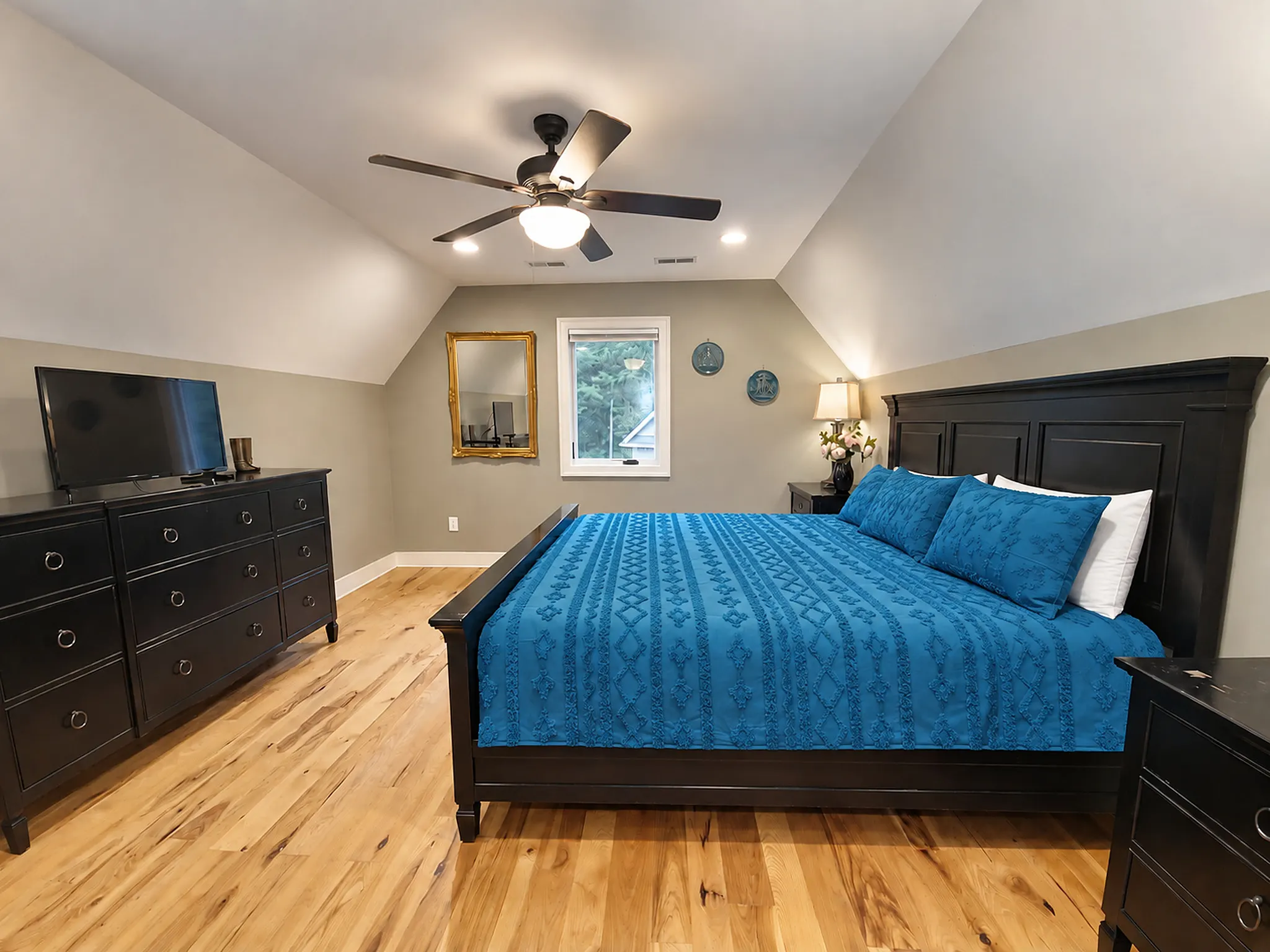 Upstairs king bedroom with teal bedding under the dormer ceiling