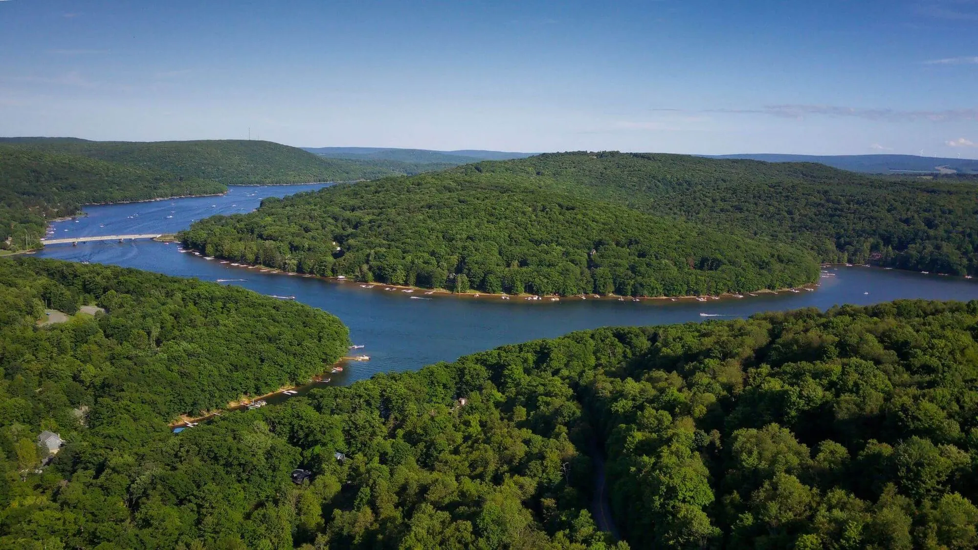 Aerial view of Deep Creek Lake's winding arms between forested ridges in summer