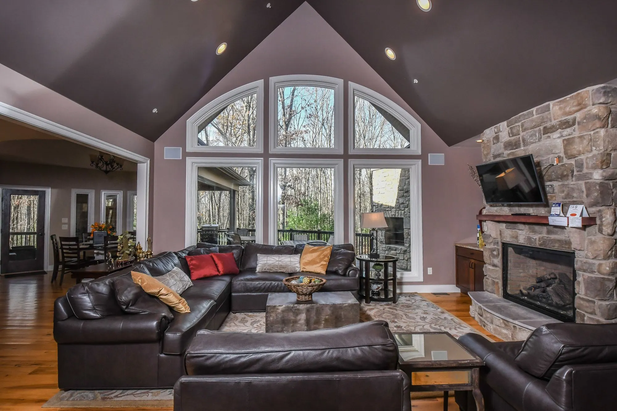 Great room with arched windows and a floor-to-ceiling stone fireplace at Woodland Chalet