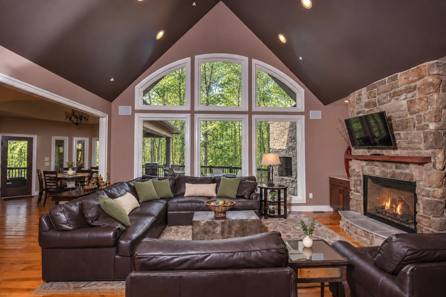 Great room with arched windows and a floor-to-ceiling stone fireplace at Woodland Chalet