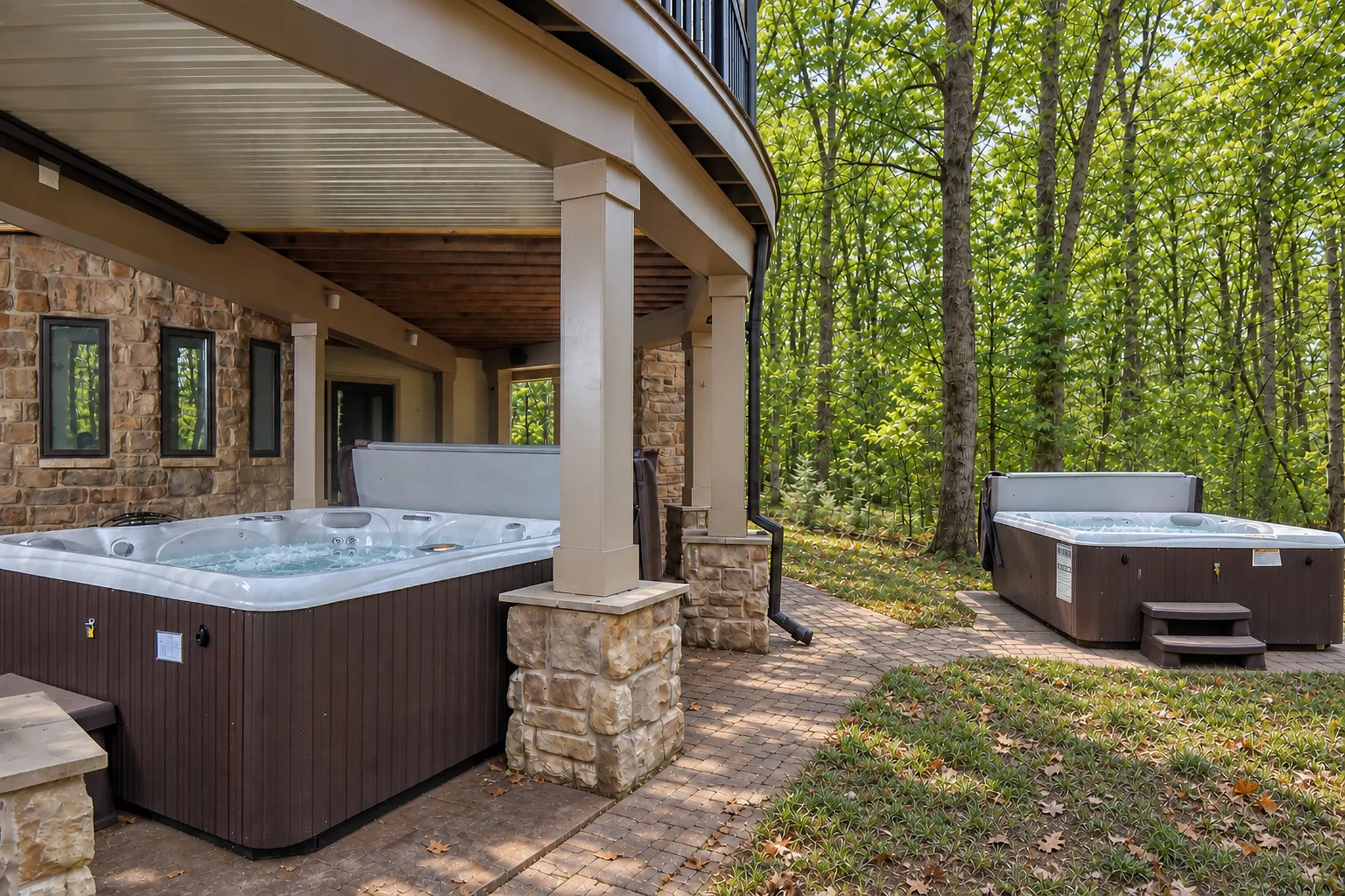 Two hot tubs on the covered patio beside a stone fireplace