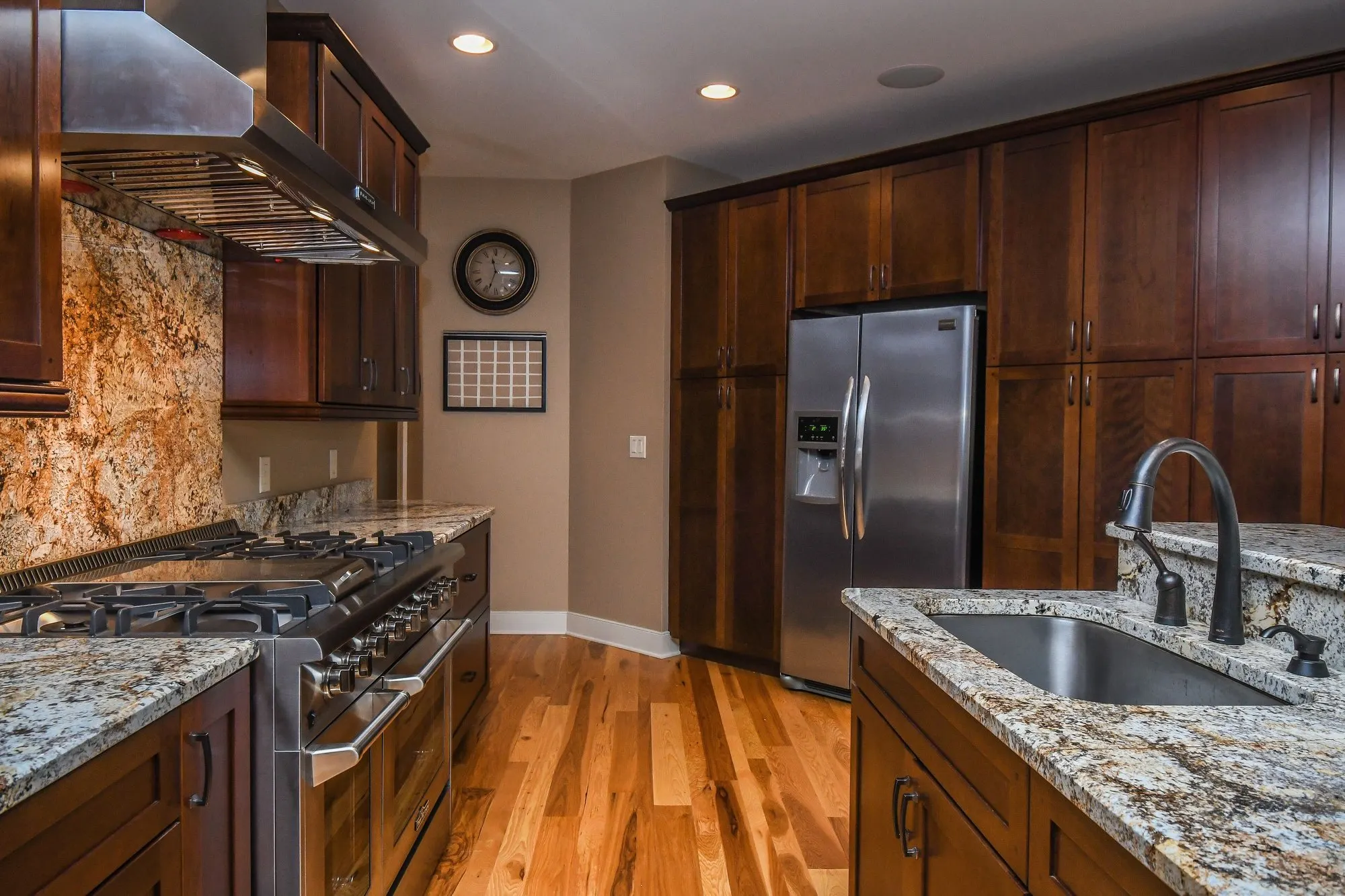 Main kitchen range with a granite backsplash and vent hood