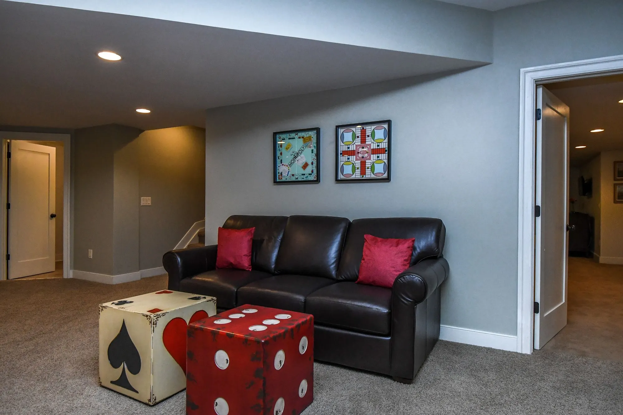 Lower level den with a leather sofa and card-suit ottomans