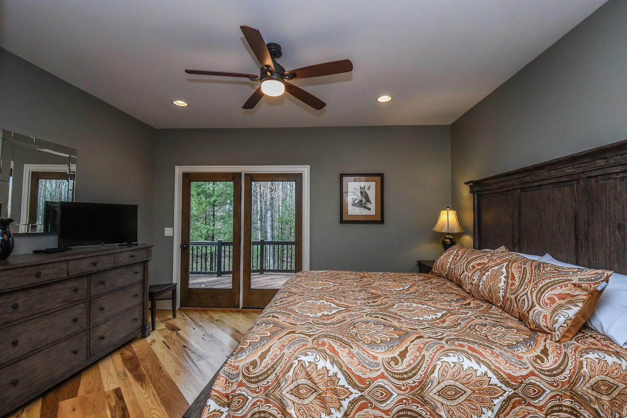 Main level bedroom with a rustic headboard and doors to the deck