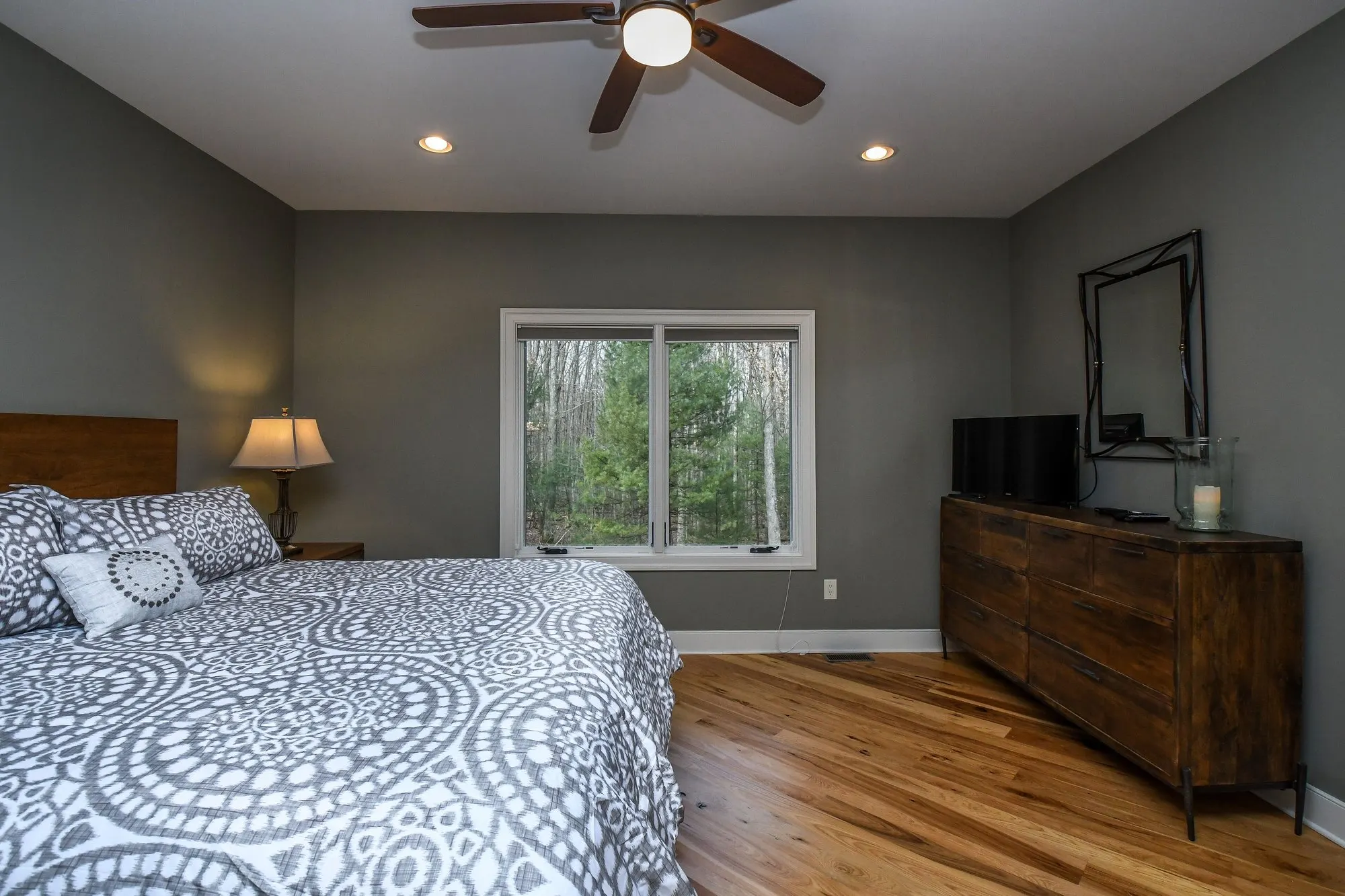 Main level bedroom with gray medallion bedding and a dresser