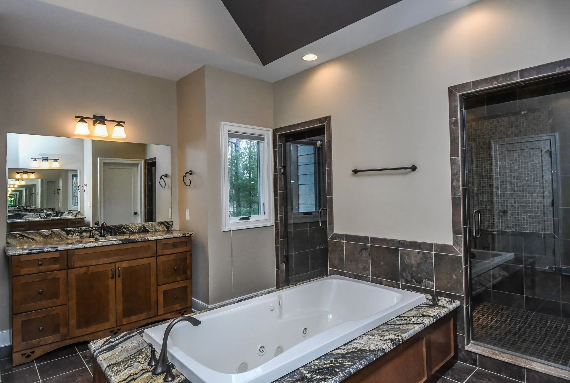 Primary bath tub and glass shower beside the window