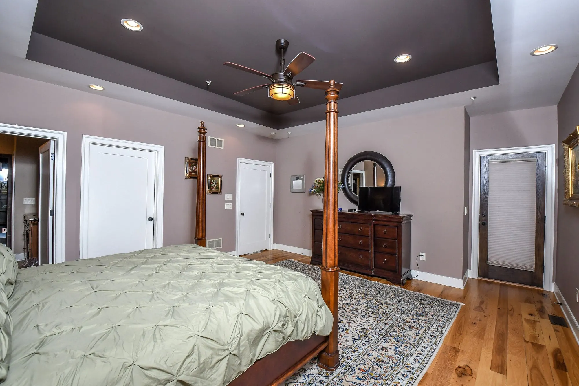 Primary suite bed beside the dresser and mirror