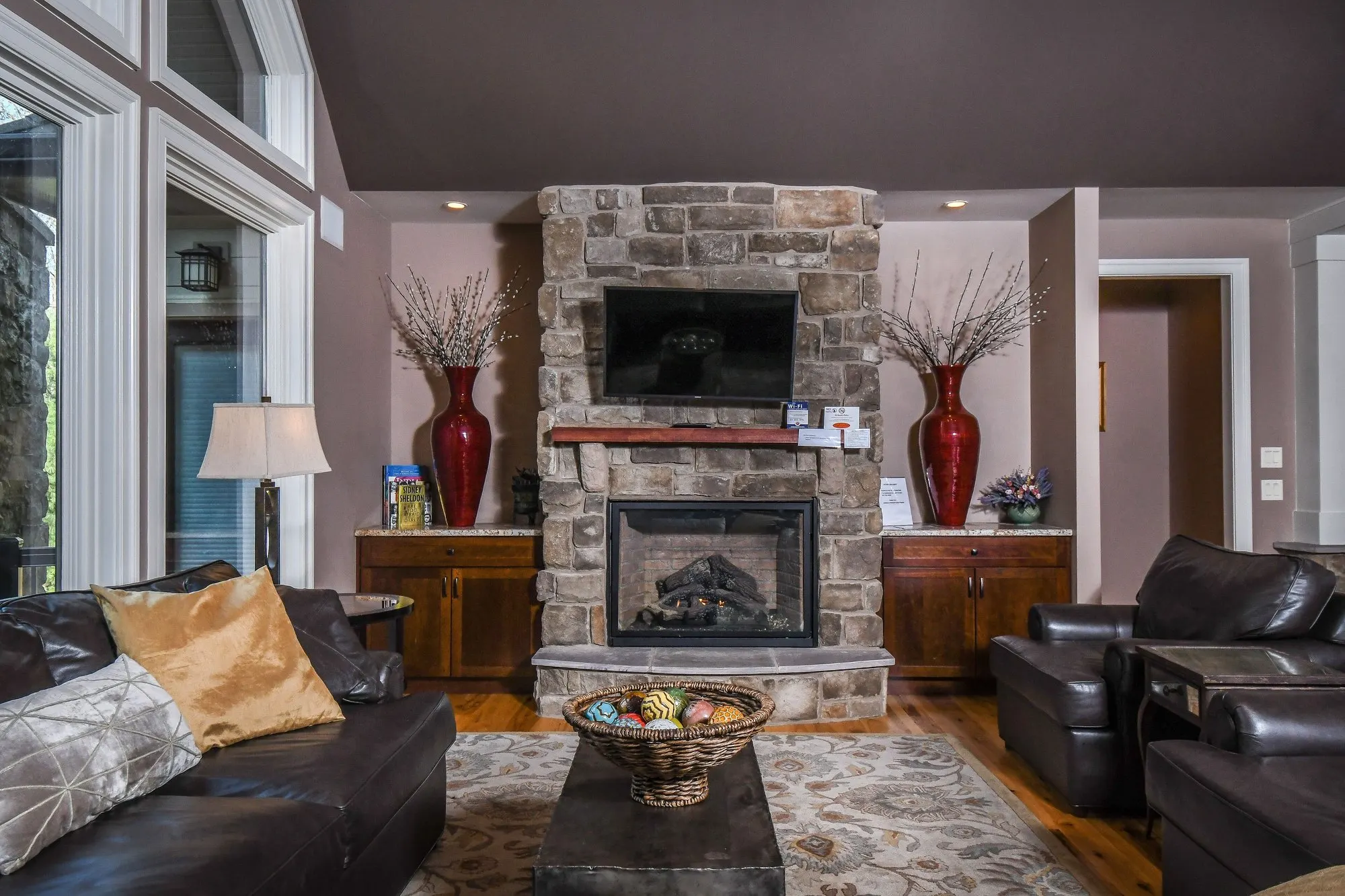 Sitting room with the corner stone fireplace and television centered