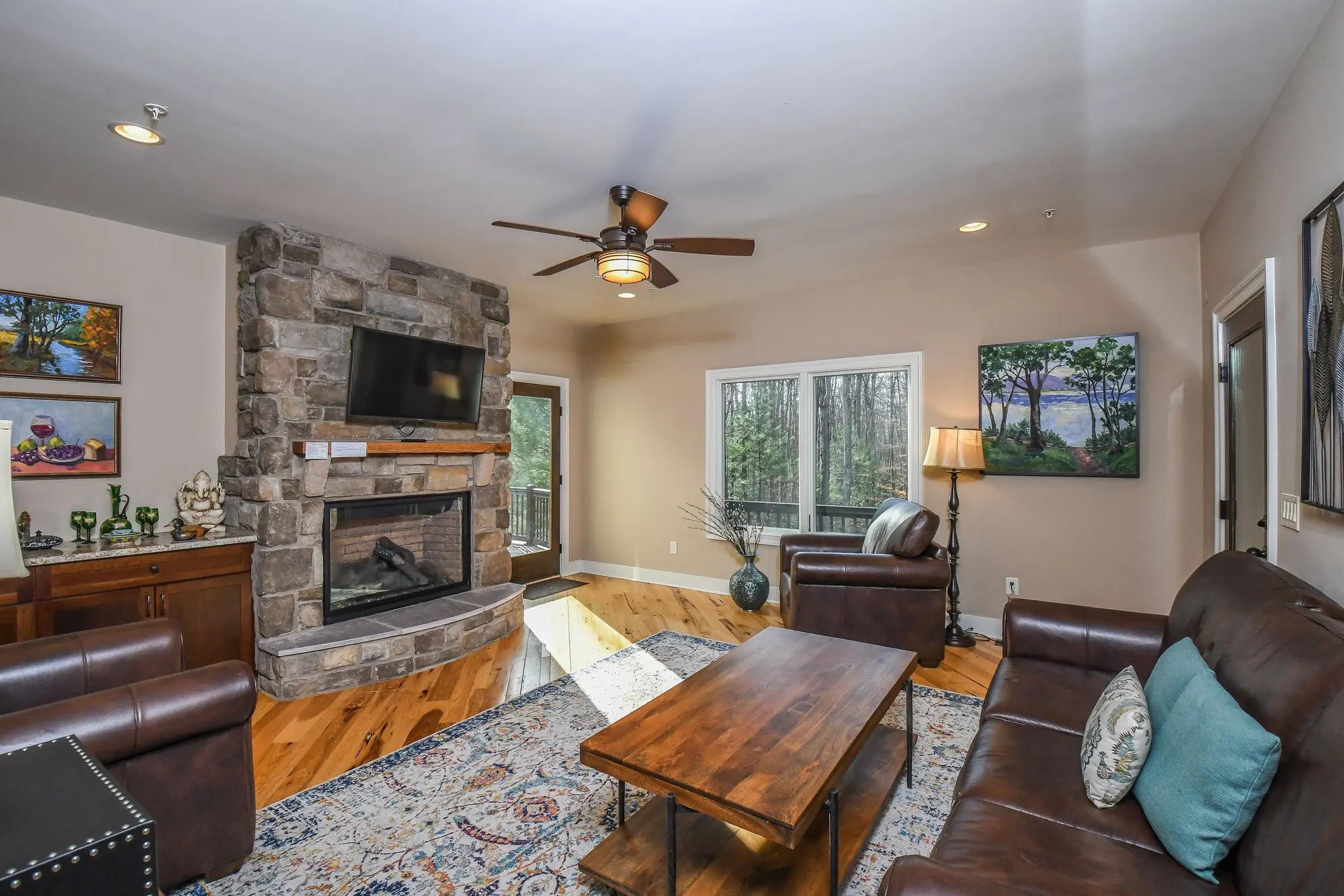 Sitting room with a corner stone fireplace and leather armchairs