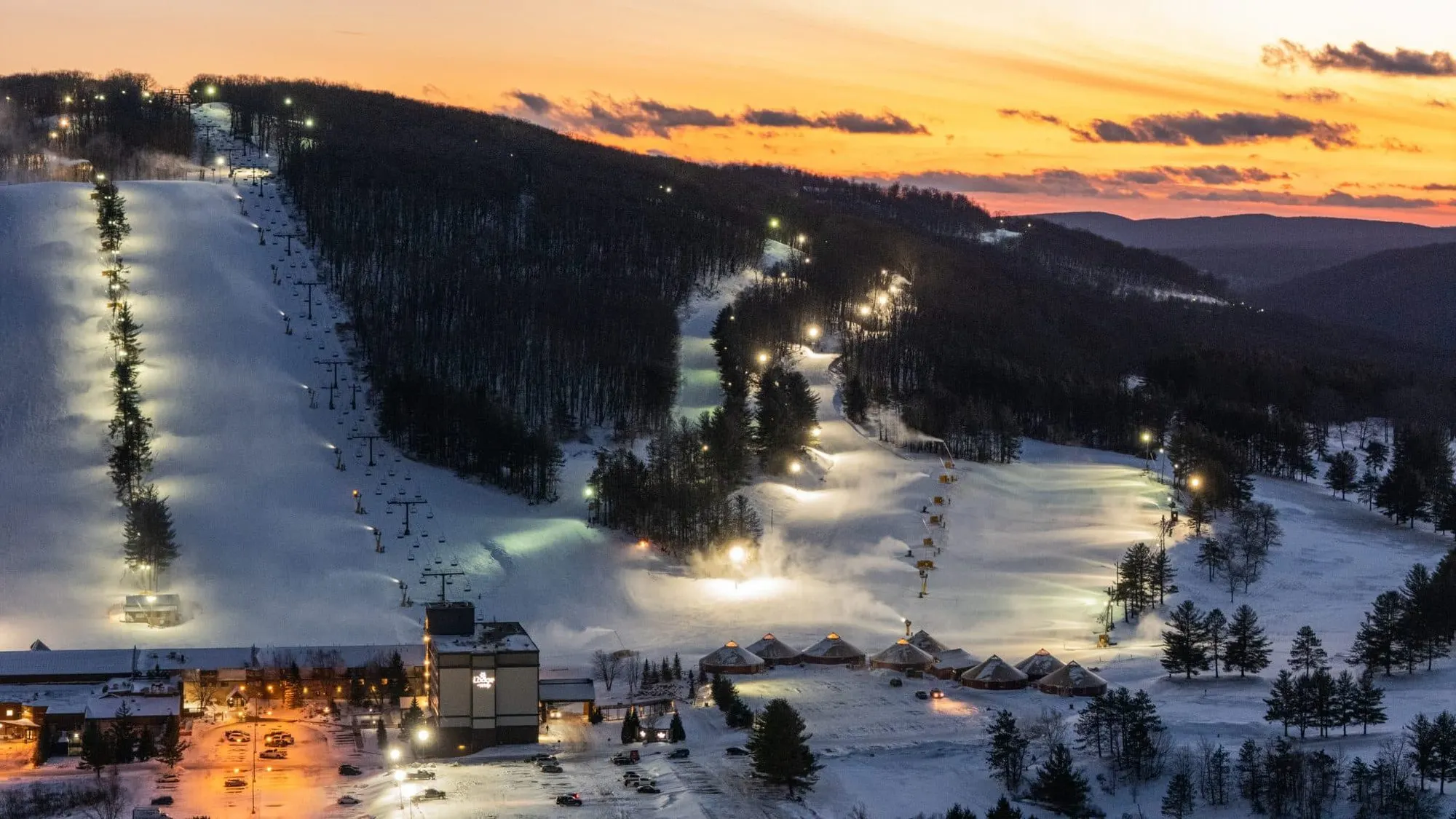 Wisp Resort's lit ski trails, lifts and base lodge at dusk, seen from above