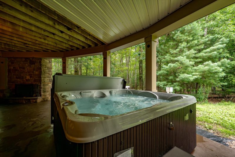 Outdoor hot tub on the lower patio surrounded by forest at Woodland Chalet